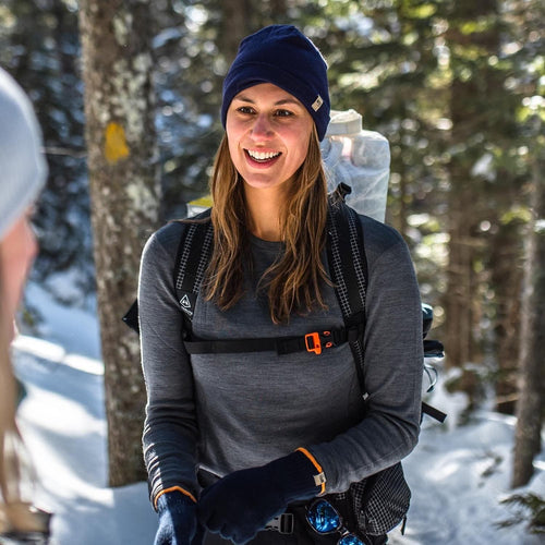 Woman in winter gear smiling in a snowy forest