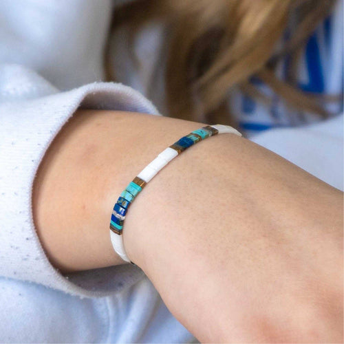 Close-up of a wrist wearing a colorful beaded bracelet with a blurred background
