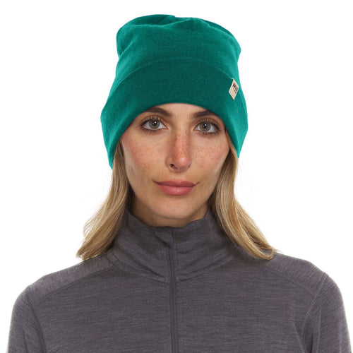 Woman wearing a teal beanie with a logo on a white background