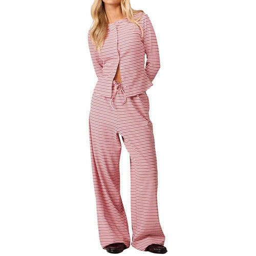 A woman modeling a pink and white striped two-piece lounge set consisting of a long-sleeve top with a front cutout and drawstring waist, paired with matching wide-leg pants, against a plain white background.