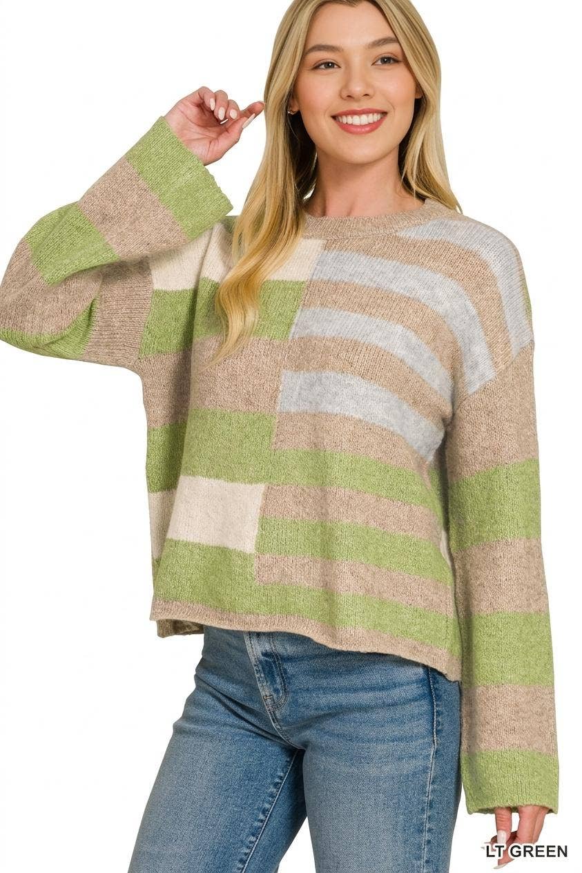 A woman wearing a fuzzy knit sweater with wide horizontal stripes in light green, beige, cream, and light gray, paired with blue jeans, against a plain white background.