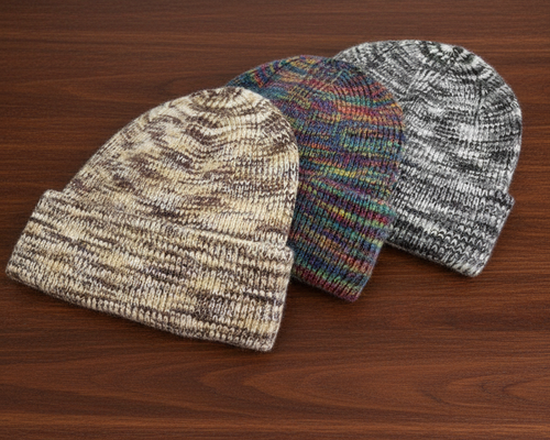Three marled knit beanie hats arranged in an overlapping fan shape on a dark brown wood-grain surface. 