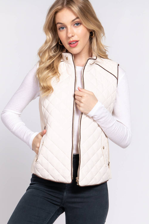 Woman wearing a beige quilted vest on a white background